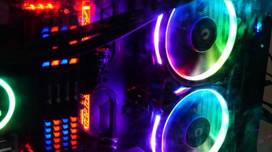 Vista interior de una torre de ordenador gaming con iluminación RGB de colores en los ventiladores, la memoria RAM y la placa base.