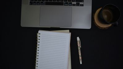 Portátil junto a bloc de notas y taza de café