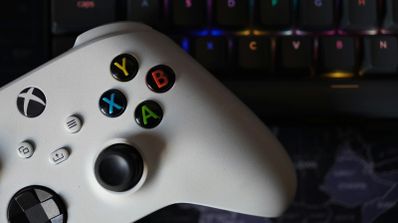 Una foto de un mando de Xbox Series, en color blanco, sobre teclado con luces RGB