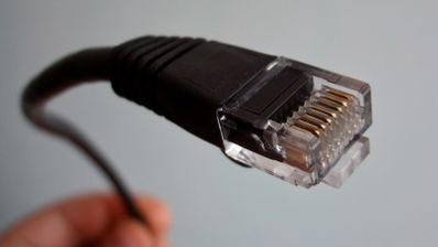 Primer plano de un conector RJ-45 de un cable de red Ethernet negro, ilustrando el hardware para una conexión a Internet por cable.