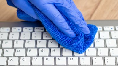 Usuario pasando trapo por teclado, simbolizando la limpieza de PC