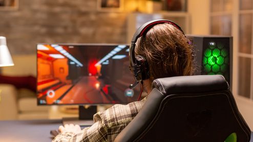 Usuario jugando a su PC con Windows 11 en una habitación bien iluminada con la característica torre gamer.