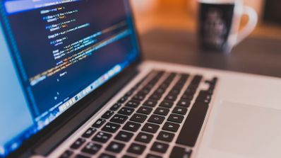 Primer plano de la pantalla de un ordenador portátil mostrando líneas de código de programación en un editor con sintaxis resaltada.