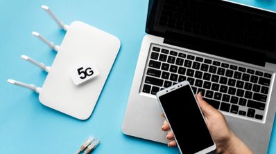 Usuario con dispositivo móvil y portátil junto a router 5G sobre superficie azulada.