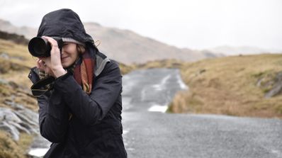 Mujer en la naturaleza tomando una foto con su cámara.