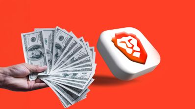 Una mano sosteniendo un abanico de billetes de dólares junto al logotipo del navegador Brave sobre un fondo naranja intenso.
