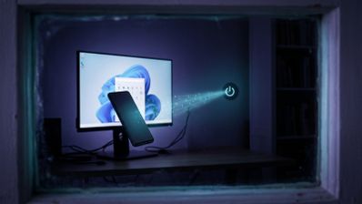 Un teléfono móvil levita frente a un monitor con Windows 11 mientras un haz de luz con código binario se dirige hacia un icono flotante de apagado.