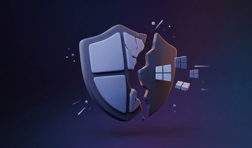 Representación tridimensional de un escudo con el logotipo de Windows roto por la mitad sobre un fondo oscuro.