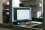 Monitor de ordenador en un escritorio mostrando una interfaz de Windows con una aplicación de gestión de datos organizada en tablas.