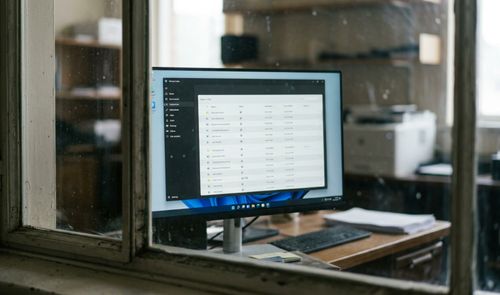 Monitor de ordenador en un escritorio mostrando una interfaz de Windows con una aplicación de gestión de datos organizada en tablas.