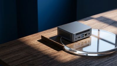 Mini PC GMKtec G10 de color gris sobre una superficie de madera y cristal mostrando sus puertos traseros.
