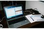 Ordenador portátil sobre un escritorio mostrando aplicaciones de Microsoft Office divididas en pantalla junto a notas físicas.