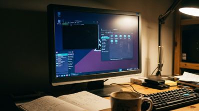Monitor de escritorio mostrando la interfaz de usuario de MX Linux con varias ventanas abiertas sobre un escritorio de madera.