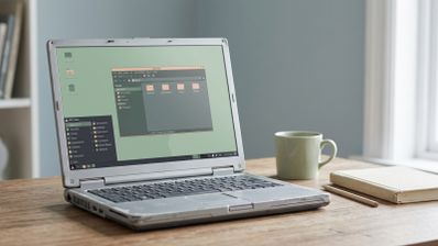 Ordenador portátil antiguo con marcas de desgaste ejecutando la interfaz de MX Linux Fluxbox sobre una mesa de madera.