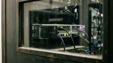Primer plano de una tarjeta gráfica instalada en un servidor rack con cables conectados visto a través de un panel de cristal.
