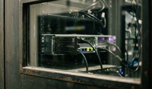 Primer plano de una tarjeta gráfica instalada en un servidor rack con cables conectados visto a través de un panel de cristal.