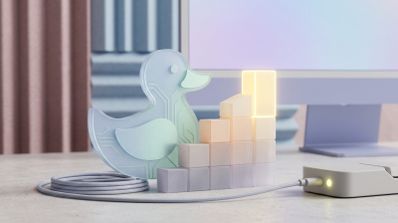 Figura de cristal con forma de pato y circuitos internos junto a una gráfica de barras ascendente iluminada frente a un monitor.