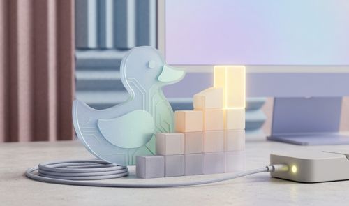 Figura de cristal con forma de pato y circuitos internos junto a una gráfica de barras ascendente iluminada frente a un monitor.