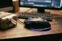 Ratón Razer Basilisk V3 con iluminación RGB sobre un escritorio de madera junto a un paquete de Amazon con una etiqueta de precio.