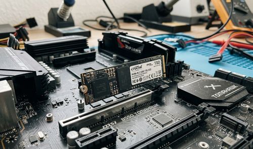 Unidad SSD NVMe M.2 instalada en la ranura de una placa base MSI B550 TOMAHAWK sobre un banco de trabajo.