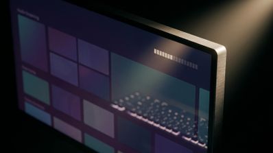 Detalle de una pantalla de ordenador que muestra una interfaz de streaming con bloques de contenido de colores y un teclado reflejado en el panel.