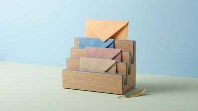 Organizador de madera con varios sobres de colores apilados y una pluma dorada en la base.
