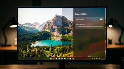 Interfaz de Windows 11 con el panel de accesibilidad abierto mostrando controles para ajustar el contraste y el brillo sobre un fondo de paisaje montañoso.