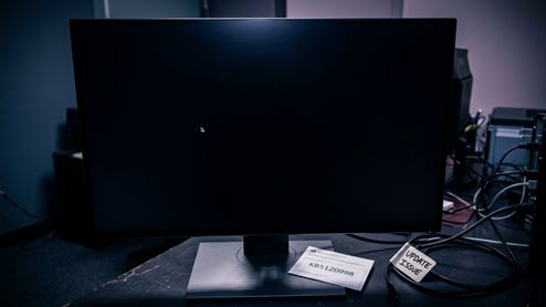 Monitor de ordenador encendido con la pantalla completamente negra y solo el cursor del ratón visible sobre una mesa de trabajo.