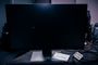 Monitor de ordenador encendido con la pantalla completamente negra y solo el cursor del ratón visible sobre una mesa de trabajo.