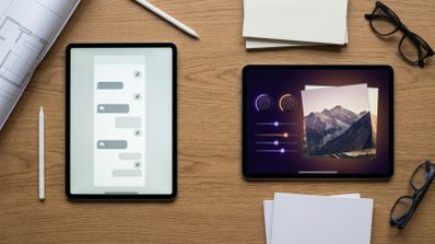 Dos tabletas sobre una mesa de madera, una mostrando una interfaz de chat y la otra controles de edición de imagen sobre una fotografía de montañas.