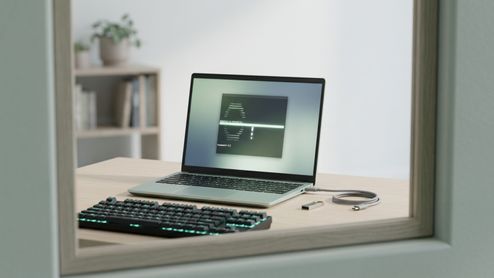 Ordenador portátil ejecutando una consola de comandos de Arch Linux sobre una mesa de madera junto a un teclado mecánico y una memoria USB.