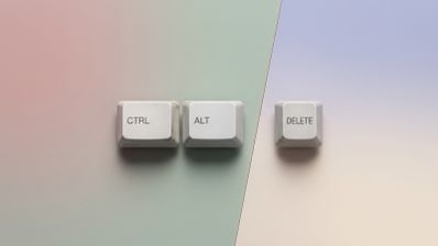 Tres teclas blancas de un teclado clásico con las etiquetas CTRL, ALT y DELETE dispuestas horizontalmente sobre un fondo de tonos pastel.