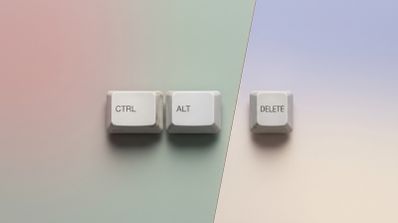 Tres teclas blancas de un teclado clásico con las etiquetas CTRL, ALT y DELETE dispuestas horizontalmente sobre un fondo de tonos pastel.