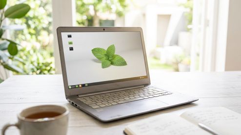 Ordenador portátil con el sistema operativo Linux Mint en pantalla sobre una mesa blanca.