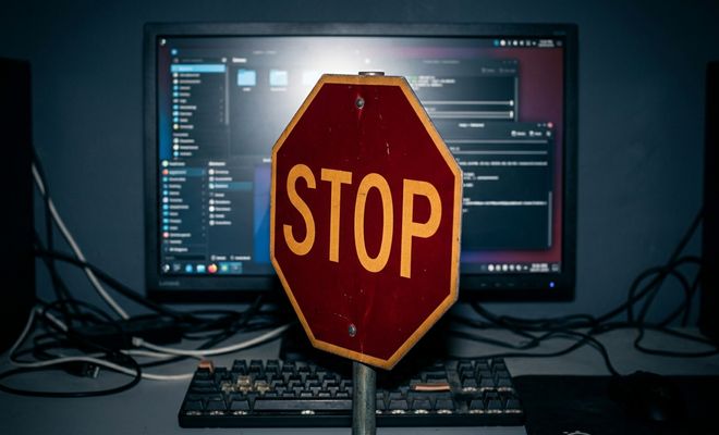 Señal de tráfico de stop frente a un monitor de ordenador que muestra un escritorio de Linux con varias ventanas abiertas.