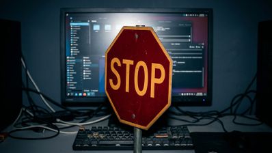 Señal de tráfico de stop frente a un monitor de ordenador que muestra un escritorio de Linux con varias ventanas abiertas.