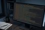 Monitor de ordenador en un escritorio oscuro que muestra la interfaz de FerrisPad con numerosas líneas de código y texto.