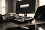 Manos de una persona utilizando un teclado mecánico frente a un monitor que muestra la interfaz de búsqueda de Flow Launcher en Windows.