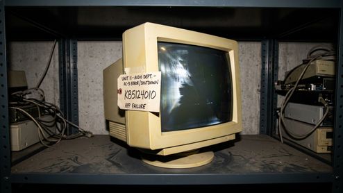 Monitor de tubo antiguo en una estantería metálica con una nota adhesiva que indica un error de audio AC-3 y el código de actualización KB5124010.