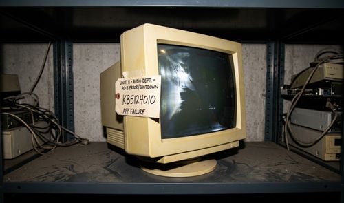 Monitor de tubo antiguo en una estantería metálica con una nota adhesiva que indica un error de audio AC-3 y el código de actualización KB5124010.