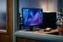 Monitor de ordenador mostrando el escritorio de KDE Plasma 6.8 con widgets de sistema y un disco duro externo conectado sobre una mesa de madera.