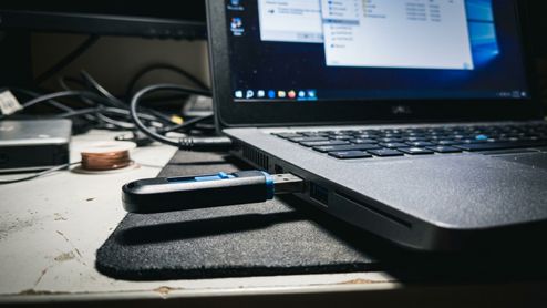Memoria USB conectada al puerto lateral de un ordenador portátil con la pantalla encendida mostrando el explorador de archivos.