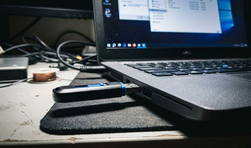 Memoria USB conectada al puerto lateral de un ordenador portátil con la pantalla encendida mostrando el explorador de archivos.