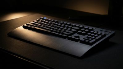 Teclado Logitech G213 Prodigy con retroiluminación azul y reposamanos integrado sobre una alfombrilla oscura.