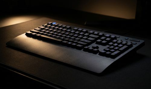 Teclado Logitech G213 Prodigy con retroiluminación azul y reposamanos integrado sobre una alfombrilla oscura.