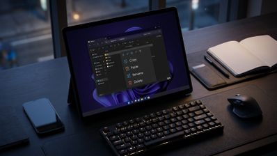 Menú contextual del Explorador de archivos de Windows 11 abierto en la pantalla de una tableta sobre un escritorio con teclado y ratón.