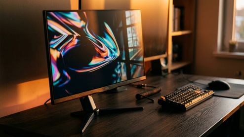 Monitor AOC 27G4ZR encendido sobre un escritorio de madera junto a un teclado mecánico y un ratón.