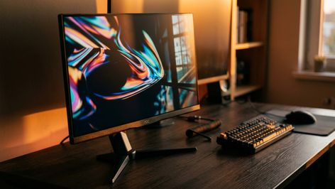 Monitor AOC 27G4ZR encendido sobre un escritorio de madera junto a un teclado mecánico y un ratón.