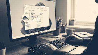 Persona utilizando un ordenador de sobremesa con la interfaz de Windows 11 y el icono de OneDrive resaltado sobre el explorador de archivos.