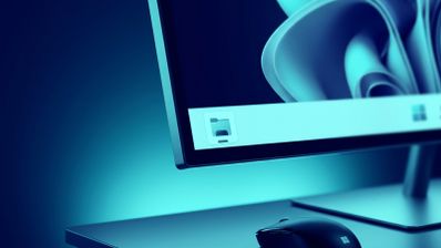 Primer plano de un monitor con la interfaz de Windows 11, mostrando el icono del Explorador de archivos en la barra de tareas sobre un escritorio iluminado en tonos azules.